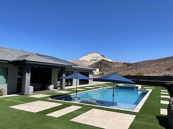 custom pool with 2 in pool loungers, 2 umbrellas and in pool table