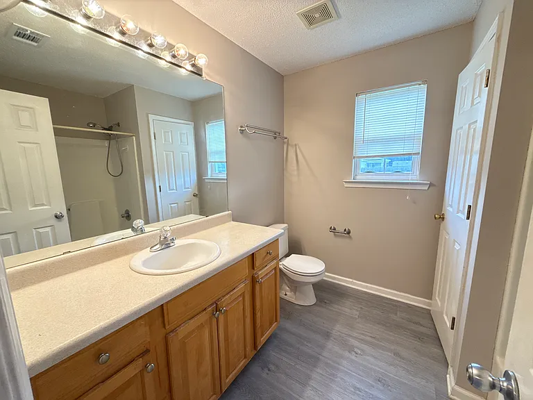 Private master bathroom with an expansive vanity mirror, ample cabinet storage, and clean finishes.