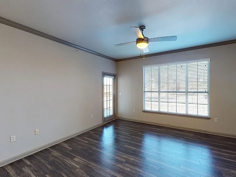 Apartment dining and living room with wood-style flooring and patio or balcony in select homes.
