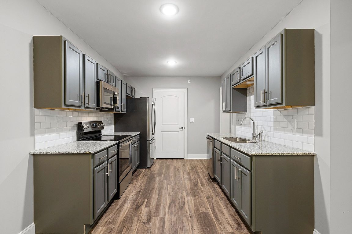 Sleek modern kitchen featuring elegant grey cabinetry, stainless steel appliances, and stylish wood flooring.