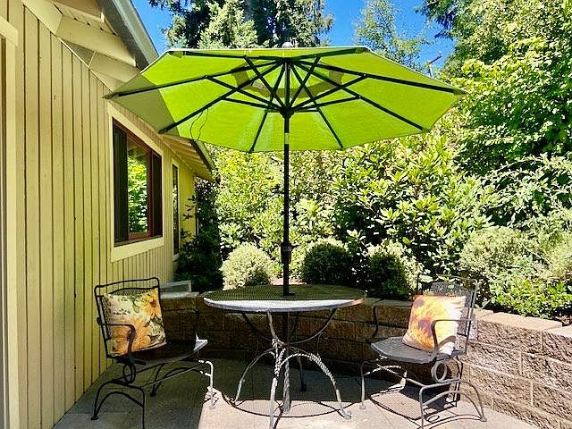 The patio is spacious with room for a BBQ, a bench and a table and chairs for outdoor dining. Surrounded by a woodland garden.