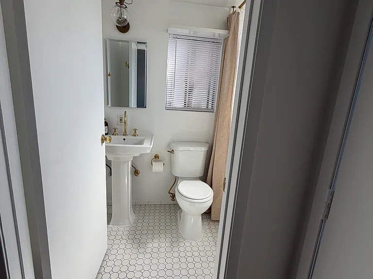 Inviting bathroom with refreshed finishes, a Kohler HydroRail 3 multifunction showerhead for a spa-like experience, and a ceiling-mounted light with an integrated fan and heater to enhance comfort throughout the year.