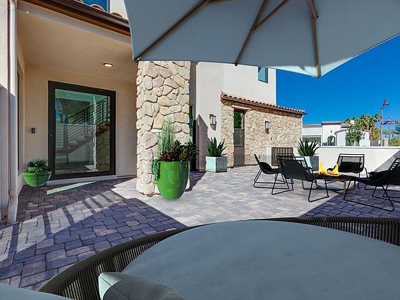 A cozy outdoor patio with stone walls, a large umbrella, and comfortable seating arrangements, set a