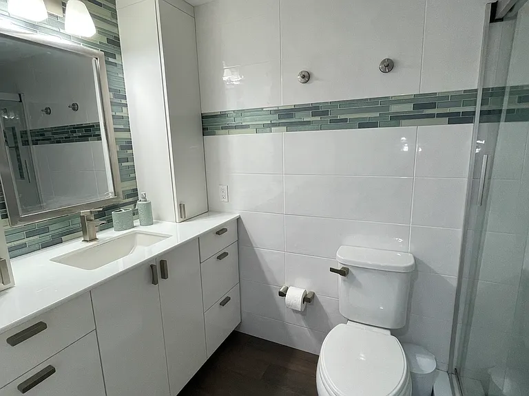 Floor to ceiling custom cabinets in wall to wall tile bathroom.