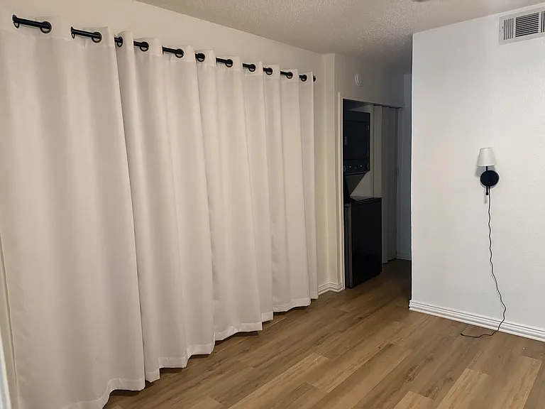 Bedroom with sconces (rechargeable) and curtained wall-length closet.