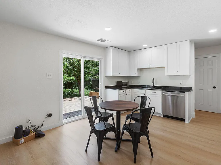 Kitchen with white cabinetry, ample counter space, and a sliding door opening to the deck for easy indoor-outdoor dining.