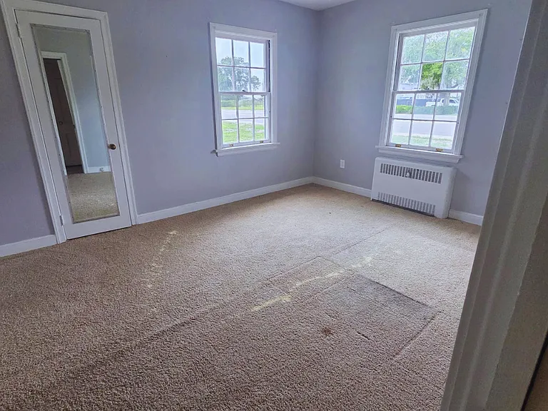 Spacious carpeted bedroom filled with natural light and comfort.