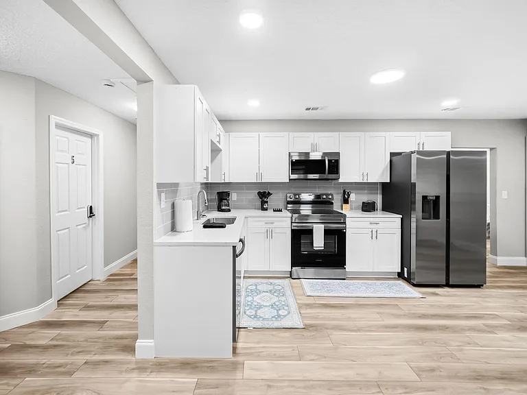 Updated kitchen with shaker cabinetry, tile backsplash, ample counter space, and stainless steel appliances for easy meal pre