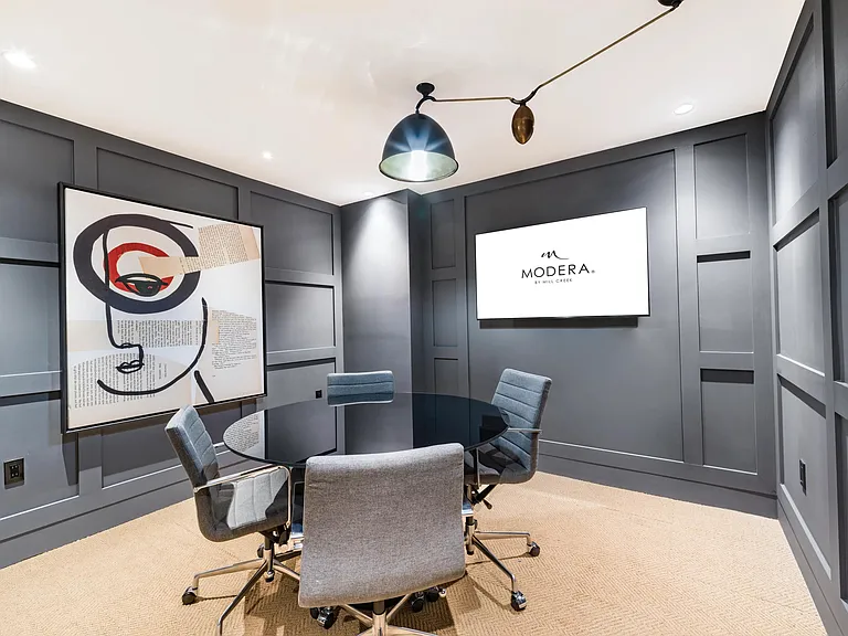 A private conference room at Modera Aventura, designed for focused meetings with tailored millwork, statement lighting, and integrated presentation technology.