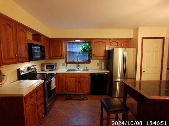 Kitchen shows farm sink, included appliances, and island with seating