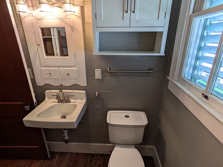 Bathroom has over toilet storage and towel racks on either side of sink.
