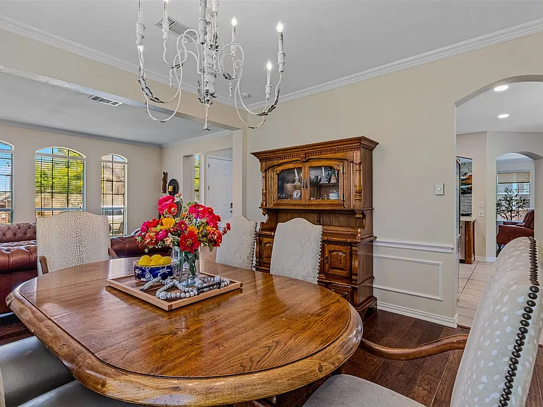Dining area with wood-finish flooring, a white chandelier, and crown molding
