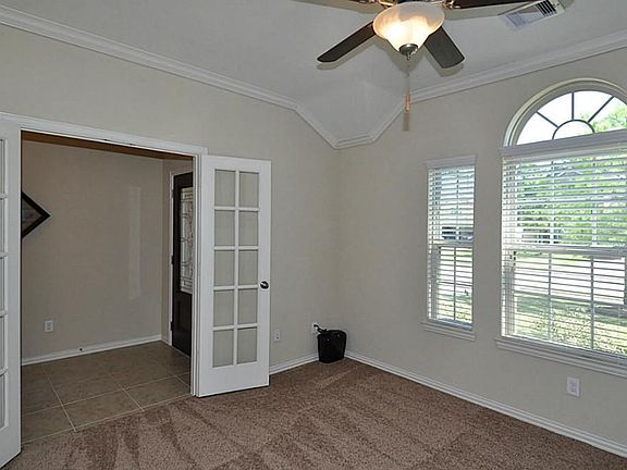 Study with oversized window enhanced with fan light, French doors, crown moulding and ceiling fan with light.