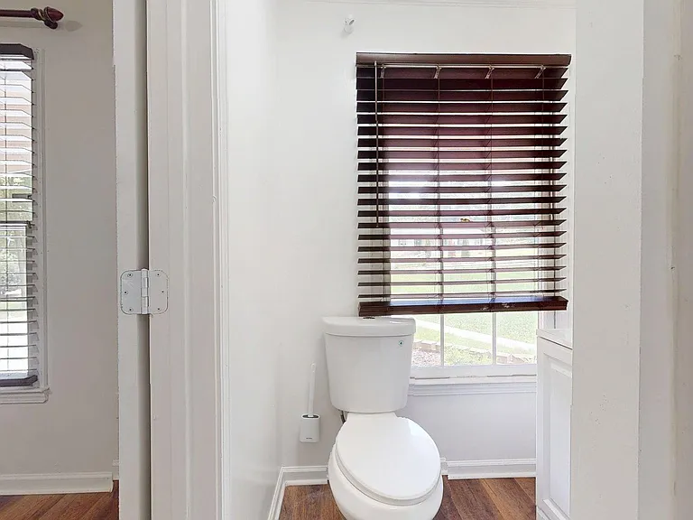 Half bath with a window for natural light, wood-look flooring, and convenient layout for everyday use.