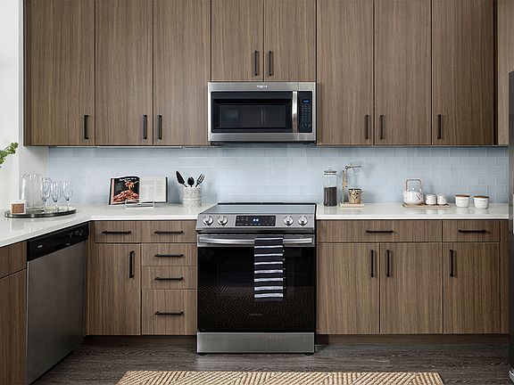 Apartment Kitchen with Stainless Steel Appliances, quartz countertop and hardwood flooring.