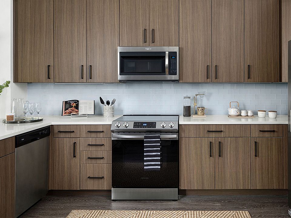 Apartment Kitchen with Stainless Steel Appliances, quartz countertop and hardwood flooring.