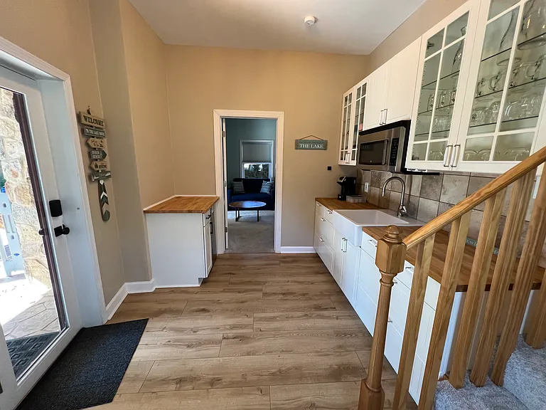 Lower level kitchenette off of the third bedroom. Includes mini refrigerator, sink, microwave, and lots of cabinet storage. The glass door leads out to the lower patio.