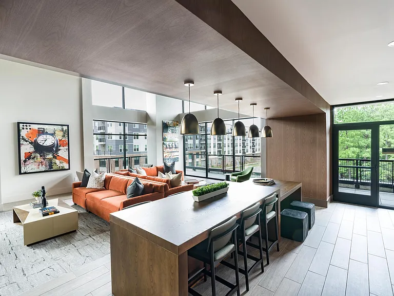 Stylish resident lounge with floor-to-ceiling windows, comfortable seating, and spaces designed for both work and relaxation.
