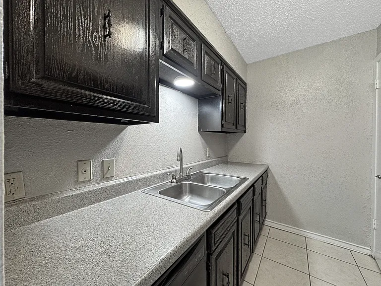 Stylish black cabinetry with stainless steel sink at Borders Apartments in Brownsville Texas.