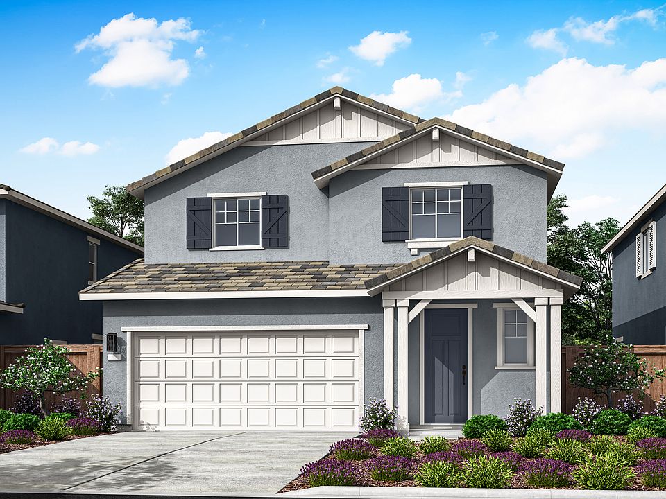 A two-story residential house with a garage, surrounded by a well-manicured lawn and colorful flower