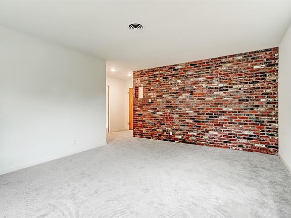 Cool interior brick wall in living room. Attic insulation. New pull down stairs to attic in hallway. Additional attic stairs in garage with decked flooring for extra storage space.