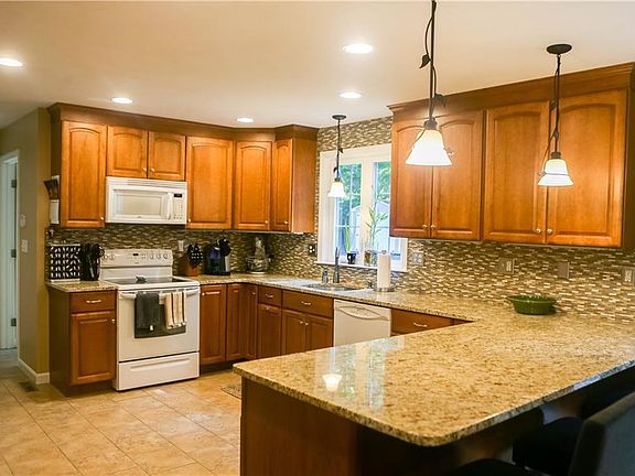 The open kitchen has granite counters and breakfast bar, a glass backsplash and all the elements to provide a wonderful heart to the home.