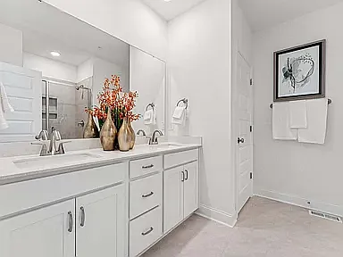The en-suite bathroom features a dual-sink vanity, a walk in shower, a private water closet, and direct access to one of two walk-in closets.