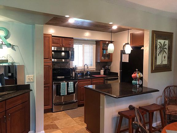 Well equipped kitchen with stainless steel appliances, granite counters and a bar.