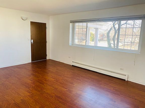 Sunny front room with central view of courtyard, trees, and side street.