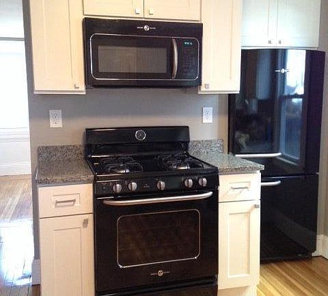 Kitchen w/ GE Artistry appliance suite, white Shaker cabinets