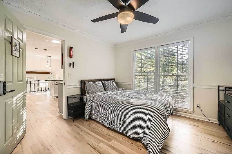 The clean, spacious room features hardwood flooring, a ceiling fan, and large windows that fill the space with natural light. It offers a bright, open layout that is easy to personalize, high-quality finishes, and a comfortable, energy-efficient environme