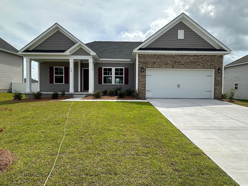 Craftsman inspired home featuring a garage and a front lawn