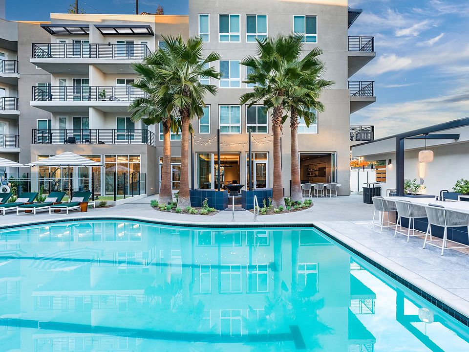 Modera Pomona offers a resort-style pool with a lounge area, seating, and palm trees for ultimate relaxation.