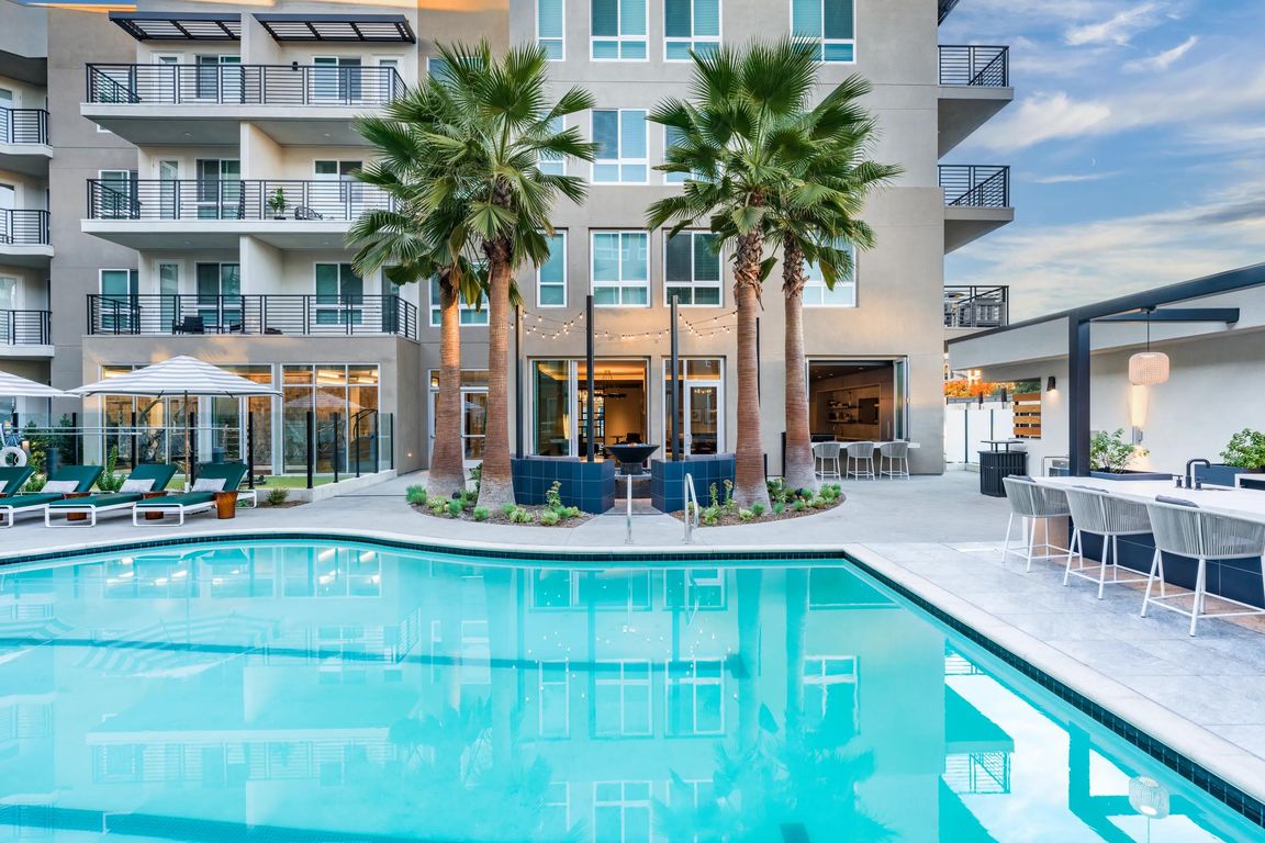 Modera Pomona offers a resort-style pool with a lounge area, seating, and palm trees for ultimate relaxation.