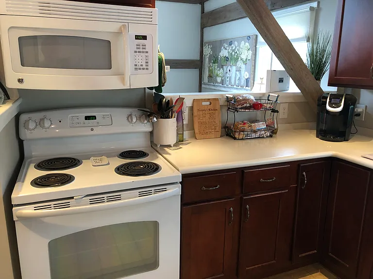 Stove, microwave, passthrough to dining room. Custom cabinetry, Corian countertops