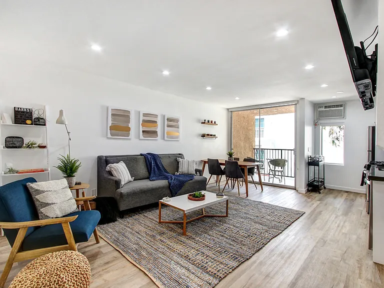 Furnished 1 Bedroom Suite, living room with cozy fireplace, wood inspired floors throughout unit