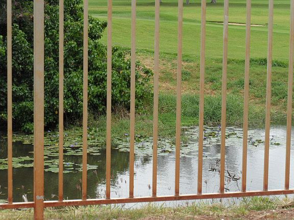 Lily/duck pond at foot of fenced patio & golf course