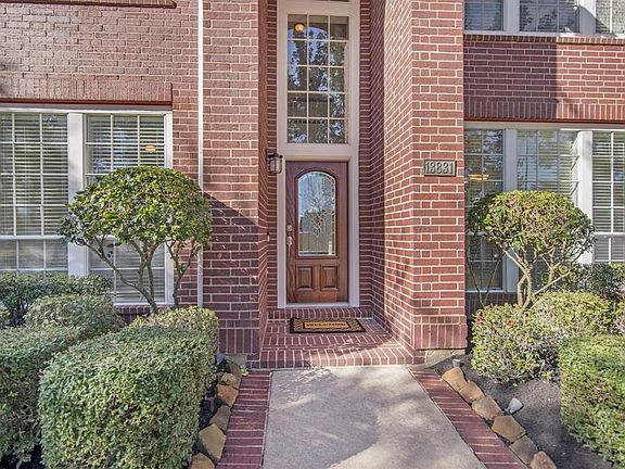 Brick walkway with recent light fixture and leaded glass front door.