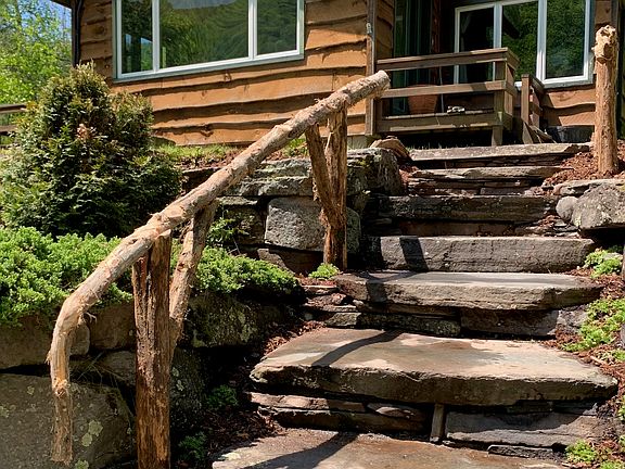 Stone stairs and rustic wood banister leading to the front deck of Grandview Cabin.
