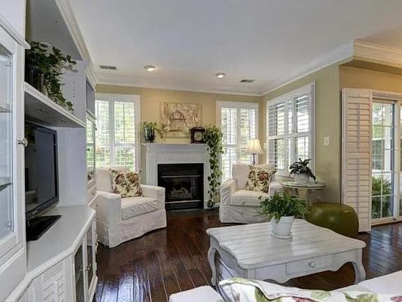 Living room with gas fireplace, crown molding, and plantation shutters
