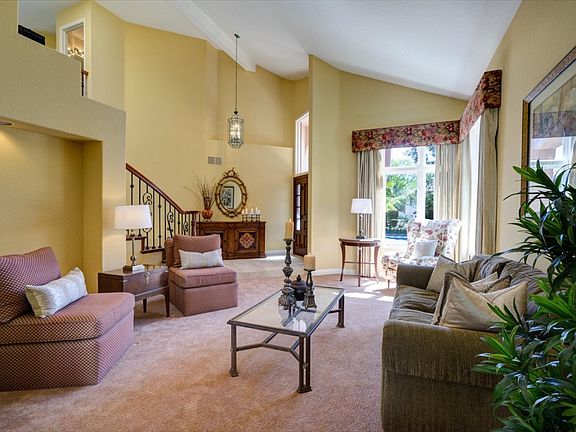 The living room has a vaulted ceiling, new carpeting, moldings and windows trimmed with custom window coverings.