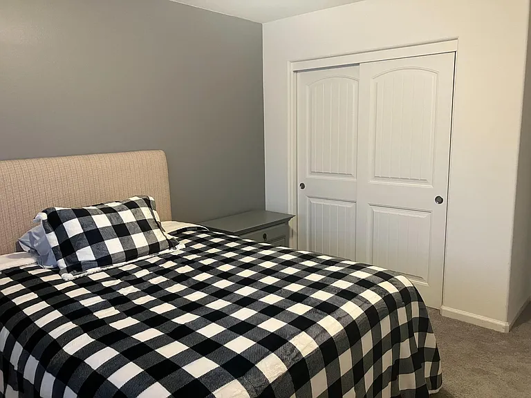 Furnished bedroom with a comfortable bed, nightstand, and a sliding-door closet for convenient storage.
