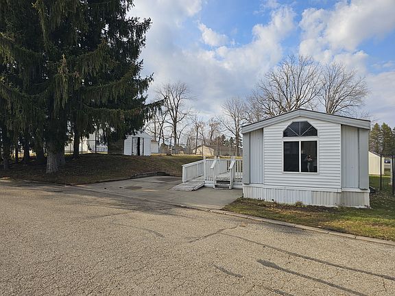 EXTERIOR OF HOME. LARGE PORCH WITH WHEELCHAIR ACCESSIBLE RAMP. LARGE DRIVEWAY FOR OFF-STREET PARKING. LARGE LOT WITH STORAGE SHED.