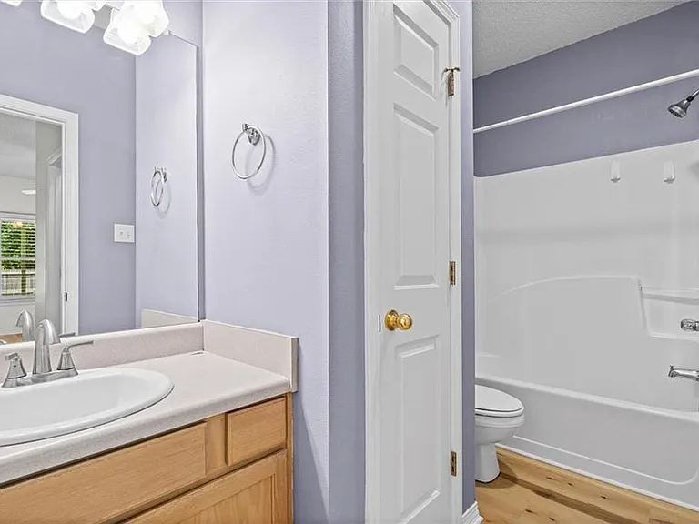 Bathroom with light wood-finish vanity, integrated sink, and brushed chrome faucet
