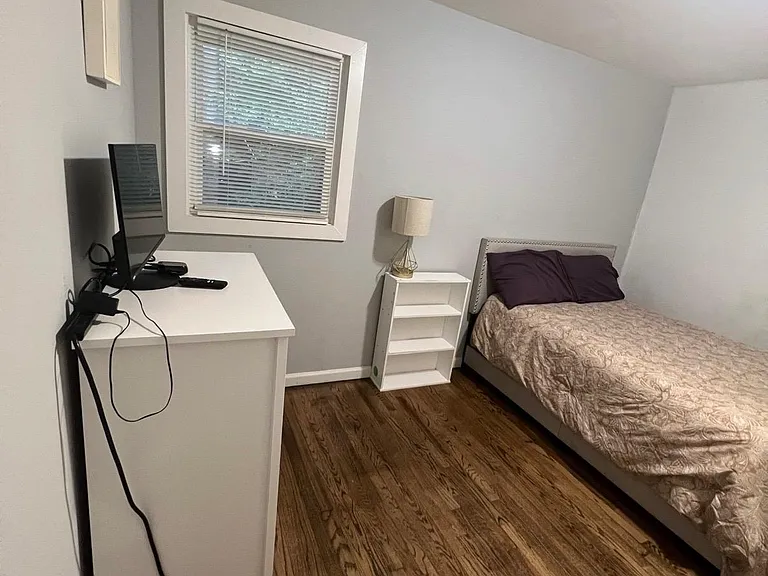 Private bedroom with wood flooring, a window with blinds, and space for a bed plus a desk or media setup.
