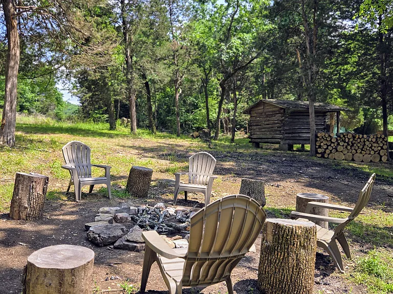 Rustic, outdoor firepit area with plenty of firewood provided