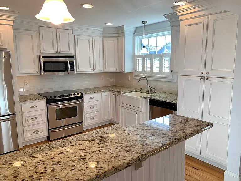 Custom white hardwood cabinets with trim and moldings galore adorn the home. The beautiful farmhouse sink complements the light filled space.