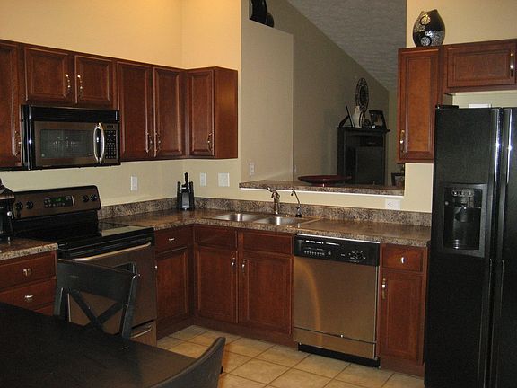 Kitchen with cherry cabinets and stainless/black appliances.