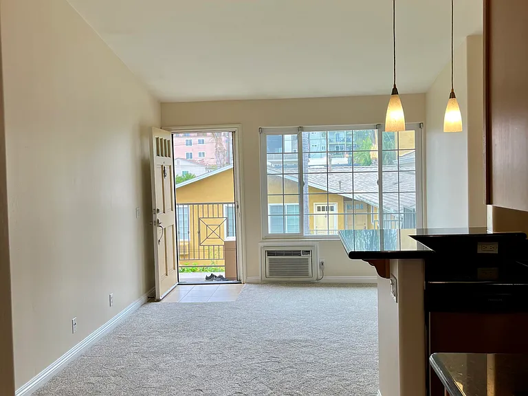 Bright and spacious living area featuring vaulted ceilings and fan.