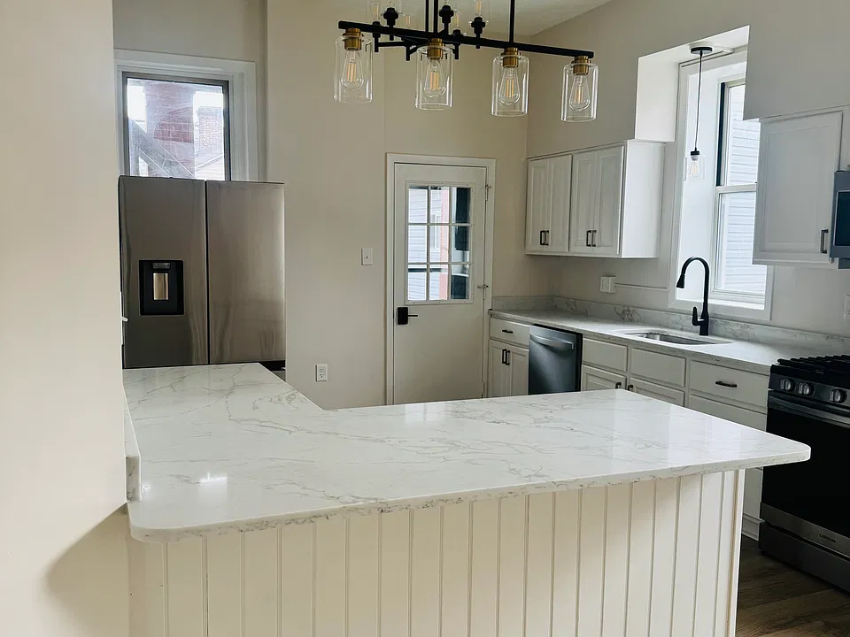 Modern kitchen features a spacious island with seating_perfect for casual dining or entertaining_paired with a sleek French door refrigerator for added style and convenience.